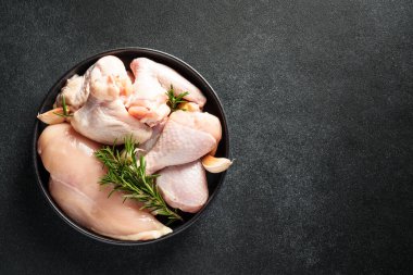 Çiğ tavuk ve baharat. Tavuğun farklı bir parçası - fileto, kanat, siyah bagetler.