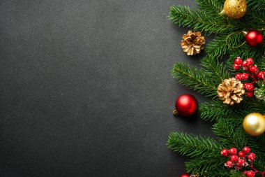 Köknar ağacı ve bayram süslemeleri ile siyah Noel arka planında yatıyordu. Tasarım için alanı kopyala.