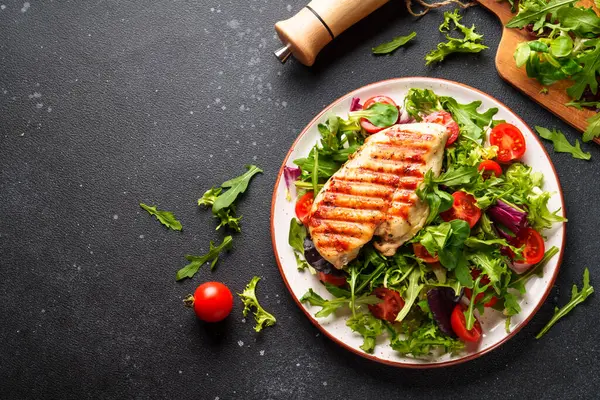 Dash diyet tabağı. Siyah arka planda taze salatalı tavuk bifteği. Kopyalama alanı olan üst görünüm.