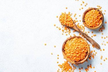 Beyaz arka planda ahşap kasede kırmızı mercimek. Kopyalama alanı olan üst görünüm.