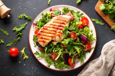 Tavuklu yeşil salata ve siyah arka planda taze sebzeler. Keto diyeti, sağlıklı yiyecekler.