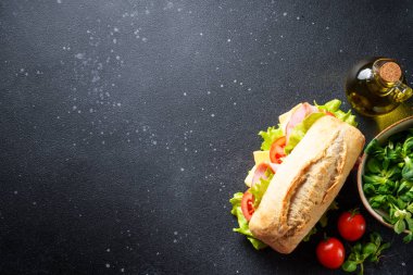 Marul, peynir, domates ve jambonlu sandviç. Mutfak masasında yemek için malzemeler var. Üst görünüm.