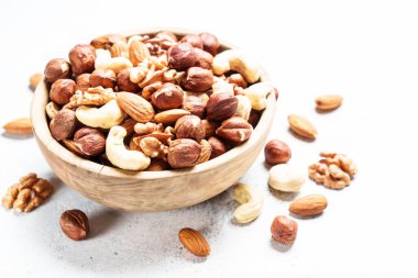 Beyaz arka planda fındık çeşitleri. Badem, fındık, ahşap kasede kaju..