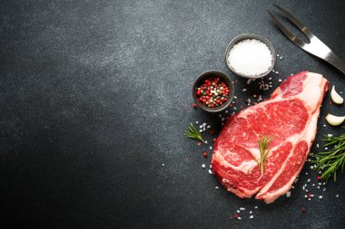 Siyah arka planda baharatlı çiğ biftek. Biftek pirzolası. Kopyalama alanı olan üst görünüm.