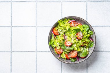 Taze yapraklı yeşil sebze salatası. Beyaz fayans arkaplanındaki üst görünüm.