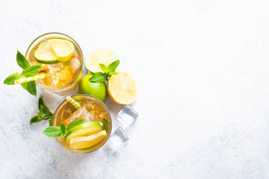 Buzlu çay. Limonlu, limonlu, naneli ve buzlu siyah çay. Soğuk limonata, yaz içkisi, beyaz arka plan. Kopyalama alanı olan üst görünüm.