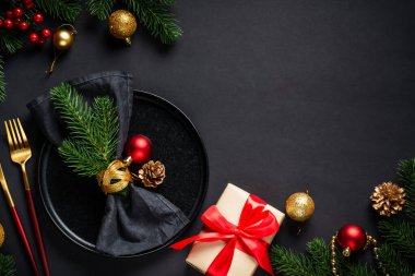 Noel yemeği. Siyah tabak, şarap kadehi, çatal bıçak takımı ve bayram süslemeleriyle Noel sofrası. Metin için boşluk ile düz uzandı.