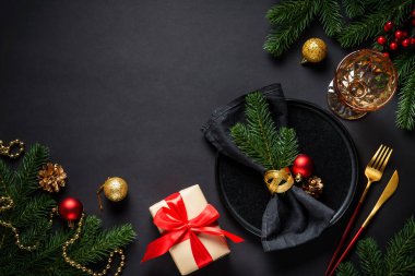 Noel yemeği. Siyah tabak, şarap kadehi, çatal bıçak takımı ve bayram süslemeleriyle Noel sofrası. Metin için boşluk ile düz uzandı.