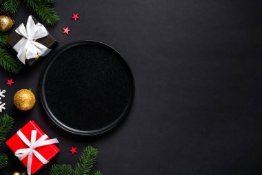 Noel yemeği. Siyah tabak, şarap kadehi, çatal bıçak takımı ve bayram süslemeleriyle Noel sofrası. Metin için boşluk ile düz uzandı.