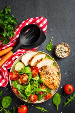 Siyah masada ızgara tavuk eti ve yeşil salata. Kopyalama alanı olan üst görünüm.