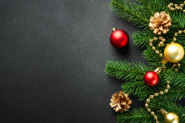 Noel arkaplanı köknar ağacı ve siyah üzerine renkli tatil süslemeleri ile yatıyordu..