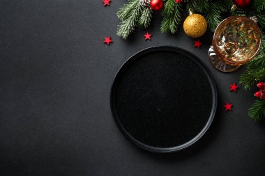Noel sofrası. Noel yemeği. Siyah arka planda siyah tabaklar, çatal bıçak takımı ve süslemeler. Kopyalama alanı olan düz.