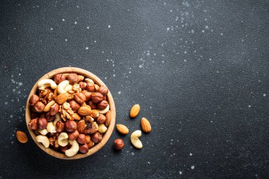 Siyah arka planda fındık çeşitleri. Badem, fındık, ahşap kasede kaju. Kopyalama alanı olan düz.