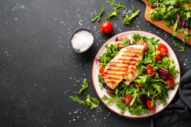 Dash diyeti, sağlıklı beslenme. Siyah arka planda taze salatalı tavuk bifteği. Kopyalama alanı olan üst görünüm.