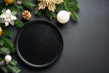 Noel sofrası. Çatal bıçaklı el işi tabaklar ve siyahta altın Noel süslemeleri. Kopyalama alanı olan düz.