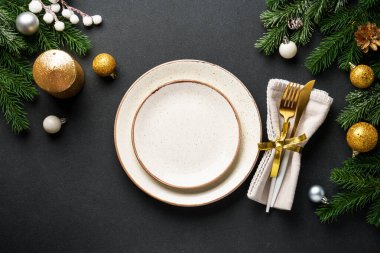Noel sofrası. Çatal bıçaklı el işi tabaklar ve siyahta altın Noel süslemeleri. Kopyalama alanı olan düz.
