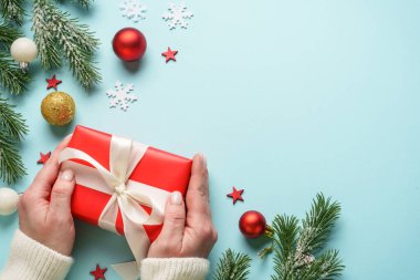 Hediye kutusunu maviye veriyorum. Noel tatiline kırmızı hediye veren bir kadın.