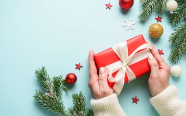 Hediye kutusunu maviye veriyorum. Noel tatiline kırmızı hediye veren bir kadın.