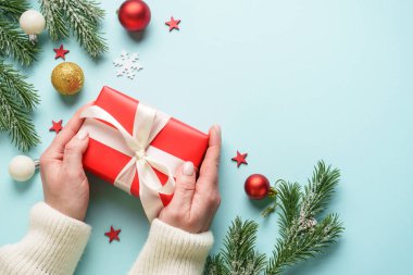 Hediye kutusunu maviye veriyorum. Noel tatiline kırmızı hediye veren bir kadın.