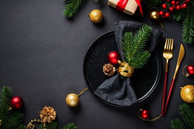 Noel yemeği. Siyah tabak, şarap kadehi, çatal bıçak takımı ve bayram süslemeleriyle Noel sofrası. Metin için boşluk ile düz uzandı.