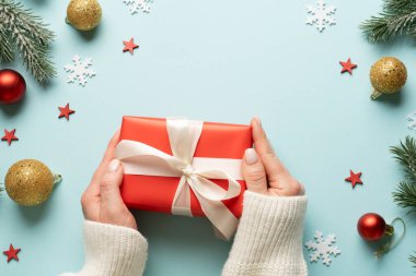 Hediye kutusunu maviye veriyorum. Noel tatiline kırmızı hediye veren bir kadın.