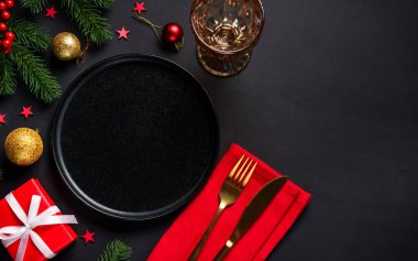Noel yemeği. Siyah tabak, şarap kadehi, çatal bıçak takımı ve bayram süslemeleriyle Noel sofrası. Metin için boşluk ile düz uzandı.