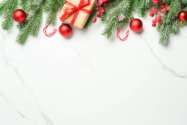 Noel arkaplanı beyazı üzerine kuruluydu. Noel kırmızı süslemeleri, hediye ve köknar ağacı. Kopyalama alanı olan kompozisyon.