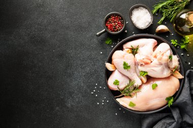 Tavuk kanadı, otlu çiğ tavuk eti. Siyah tablo üzerinde kopyalama alanı olan üst görünüm.