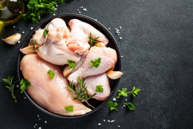 Çiğ tavuk ve baharat. Tavuğun farklı bir parçası - fileto, kanat, siyah bagetler.