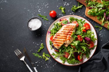 Tavuklu yeşil salata ve siyah arka planda taze sebzeler. Keto diyeti, sağlıklı yiyecekler.