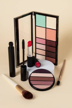 Makyaj ürünleri. Göz falı paleti, krem kavanozu, renkli arka planda ruj ve fırçalar..
