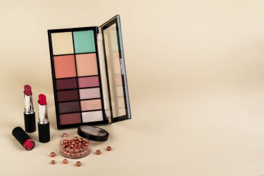 Makyaj ürünleri. Göz falı paleti, krem kavanozu, renkli arka planda ruj ve fırçalar..