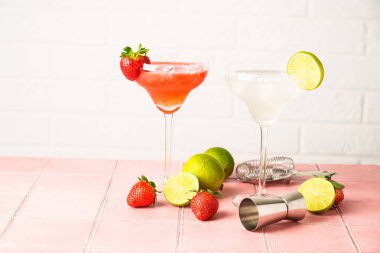 Uzun bardaklarda klasik ve çilekli margarita. Renkli tekila, buz ve limon..