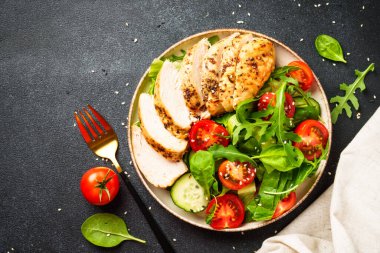 Izgara etli yeşil salata ve siyah masada taze sebzeler. Kopyalama alanı olan üst görünüm.