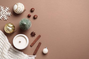 Mocha Mousse 'un moda rengi 2025 kış arka planı. Noel dekoru, mum ve beyaz örgü atkısı. Kopya alanı ile rahat Düz konum.