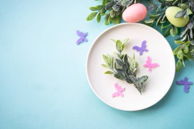 Paskalya sofrası, paskalya yemekleri. Yumurtalı beyaz tabak ve tatil süslemeleri. Kopyalama alanı olan üst görünüm.