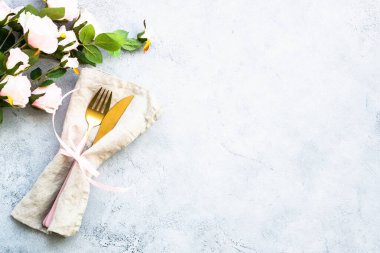 Masa dekorasyonu, modern çatal bıçak takımı ve pembe çiçeklerle süslü lüks tava dekorasyonu. Kopyalama alanı olan beyaz arkaplanda üst görünüm.