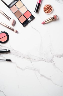 Beyaz mermer arka planda ürünler uydur. Kozmetik palet, fırçalar ve rujlar. Kopyalama alanı olan üst görünüm.