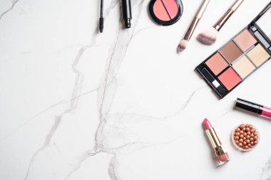 Beyaz mermer arka planda ürünler uydur. Kozmetik palet, fırçalar ve rujlar. Kopyalama alanı olan üst görünüm.