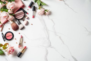 Beyaz mermer arka planda çiçekli ürünler uydur. Kozmetik palet, fırçalar ve rujlar. Kopyalama alanı olan üst görünüm.