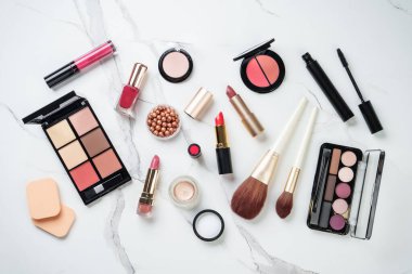 Beyaz mermer arka planda ürünler uydur. Kozmetik palet, fırça, rimel ve ruj. Düz yatıyordu.