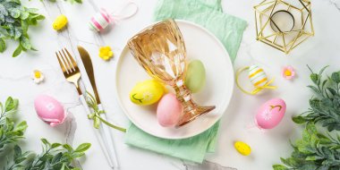 Beyaz arka planda Paskalya sofrası. Beyaz tabak, çatal bıçak takımı ve paskalya süslemeleri. Web pankartı biçimi.