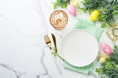 Beyaz arka planda Paskalya sofrası. Beyaz tabak, çatal bıçak takımı ve paskalya süslemeleri. Düz yatıyordu.