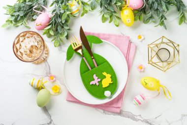 Beyaz arka planda Paskalya sofrası. Beyaz tabak, çatal bıçak takımı ve paskalya süslemeleri. Düz yatıyordu.