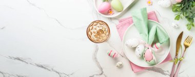 Beyaz arka planda süslemeleri olan Paskalya yemekleri. Beyaz tabak, çatal bıçak takımı ve komik paskalya süslemeleri..