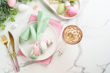Beyaz arka planda süslemeleri olan Paskalya yemekleri. Beyaz tabak, çatal bıçak takımı ve komik paskalya süslemeleri..