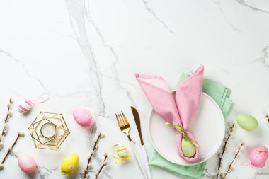 Beyaz arka planda süslemeleri olan Paskalya yemekleri. Beyaz tabak, çatal bıçak takımı ve komik paskalya süslemeleri..