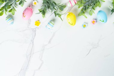 Paskalya düzlüğü arka plandaydı. Paskalya yumurtaları ve beyazın üzerindeki süslemeler. Kopyalama alanı olan düz.