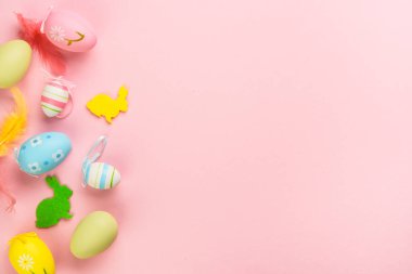Paskalya yumurtaları ve pembe arka planda süslemeler. Kopyalama alanı olan düz resim.