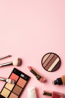 Makyaj ürünleri pembeye yatar. Göz farı, fosforlu kalem, krem, ruj ve kozmetik fırçalar..